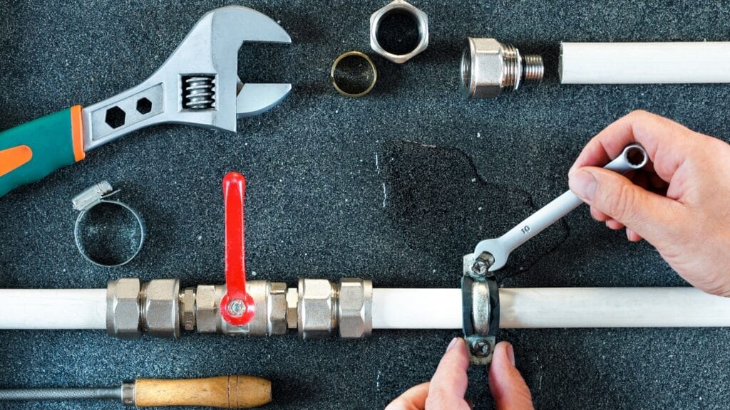 Plumber repairing a pipe valve with an adjustable wrench in Sebastian