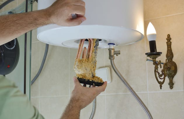 Technician removing mineral buildup from a water heater in Sebastian