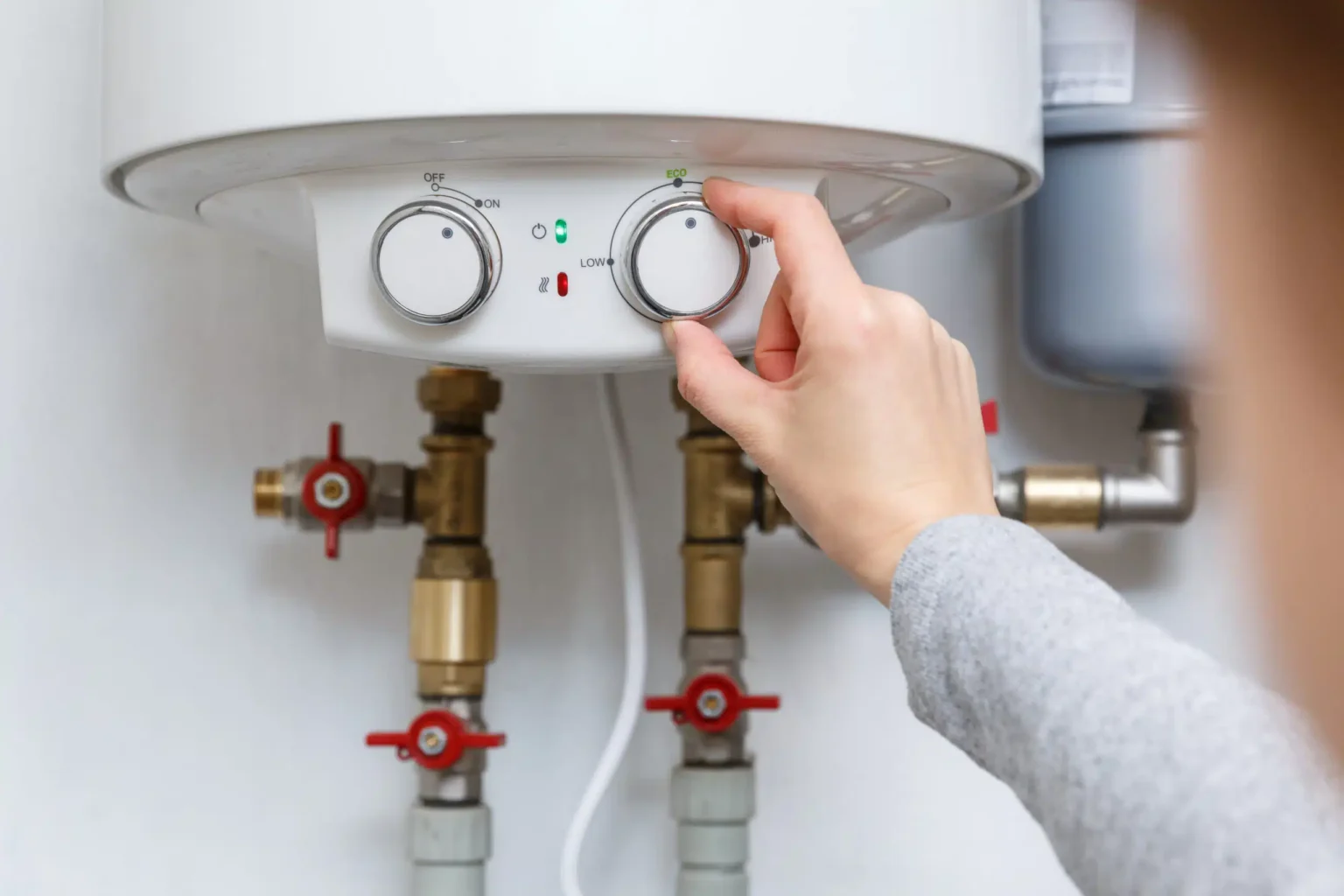 Homeowner adjusting the temperature controls on a water heater in Sebastian
